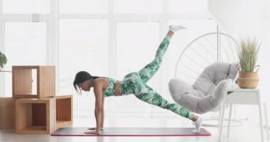 Konsantre olmuş ince, siyah kadın kalas egzersizi yapıyor. Kendinden emin Afro-Amerikan sporcu kadın eğitiminin portresi..