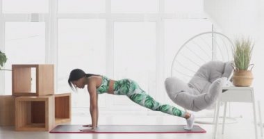 Konsantre olmuş ince, siyah kadın kalas egzersizi yapıyor. Kendinden emin Afro-Amerikan sporcu kadın eğitiminin portresi..