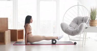 Güçlü fitness kadını yuvarlanarak miyofasyal masaj yapıyor. Genç, formda bir kadın evinde masaj yapıyor.. 