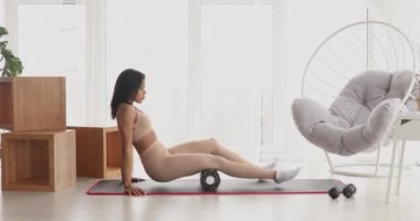 Güçlü fitness kadını yuvarlanarak miyofasyal masaj yapıyor. Genç, formda bir kadın evinde masaj yapıyor.. 