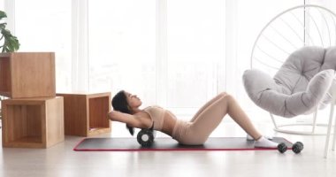 Güçlü fitness kadını yuvarlanarak miyofasyal masaj yapıyor. Genç, formda bir kadın evinde masaj yapıyor.. 