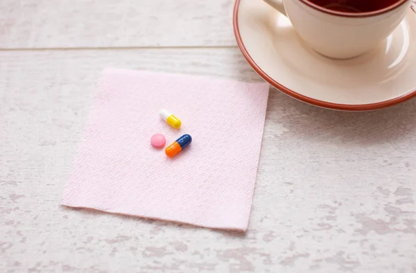 assorted colorful pills and cup on wooden table, close-up view