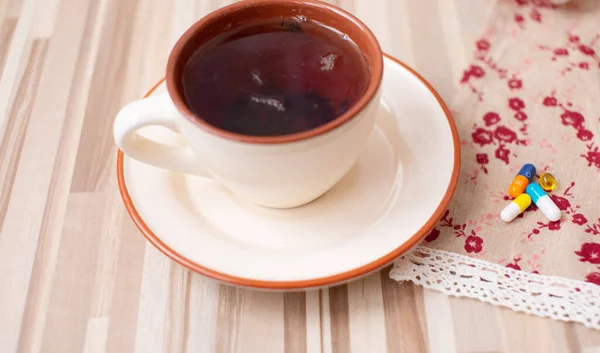 assorted colorful pills and cup on wooden table, close-up view