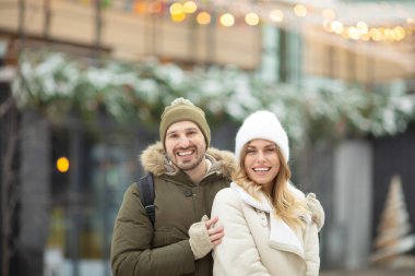 Mutlu genç çift birlikte vakit geçiriyor ve kış parkında kameraya gülümsüyor.