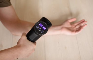 Masaj perküsyon cihazıyla el masajı yapan adamın yakın çekim görüntüsü