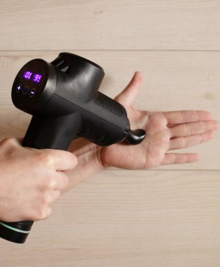 Antrenmandan sonra masaj cihazıyla el masajı yapan adamın yakın çekim görüntüsü.