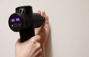 Adam antrenmandan sonra eline masaj perküsyon cihazıyla masaj yapıyor..