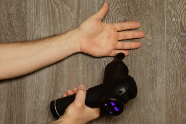 Adam eline masaj perküsyon cihazıyla masaj yapıyor. 