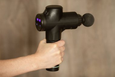 Elin terapötik vurmalı masaj tabancası tutarken yakın plan görüntüsü..