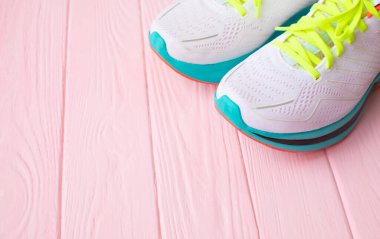 Pembe ahşap arka planda bir çift beyaz spor ayakkabının yakın plan görüntüsü