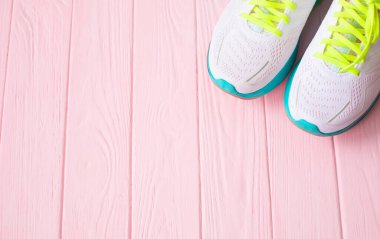 Pembe ahşap arka planda beyaz spor ayakkabıların üst görüntüsü