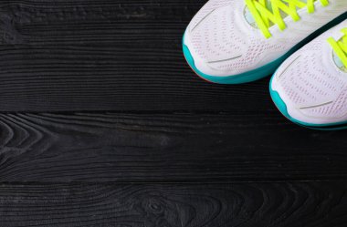 Siyah ahşap arka planda bir çift beyaz spor ayakkabının yakın plan görüntüsü