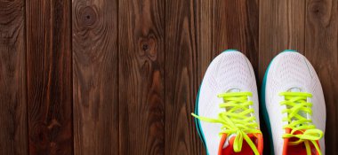 Kahverengi ahşap arka planda bir çift beyaz spor ayakkabı 