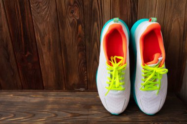 Kahverengi ahşap arka planda bir çift beyaz spor ayakkabı 