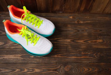 Kahverengi ahşap arka planda bir çift beyaz spor ayakkabı 