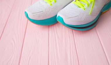 Pembe ahşap arka planda bir çift beyaz spor ayakkabının yakın plan görüntüsü