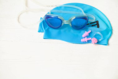 Yüzme ekipmanları: ahşap bir arka planda kep ve gözlük.