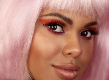 Yaratıcı makyajlı ve pembe saçlı güzel bir Afrikalı Amerikalı kızın yakın plan portresi.