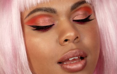 Yaratıcı makyajlı ve pembe saçlı güzel bir Afrikalı Amerikalı kızın yakın plan portresi.