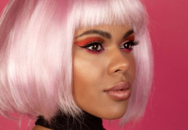 Pembe arka planda pembe saçlı seksi siyahi kadının yakın plan görüntüsü.