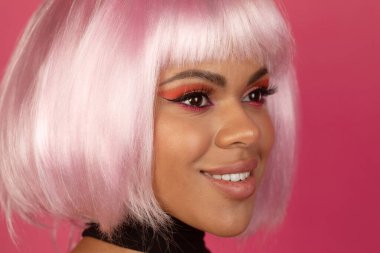 Pembe arka planda pembe saçlı seksi siyahi kadının yakın plan görüntüsü.