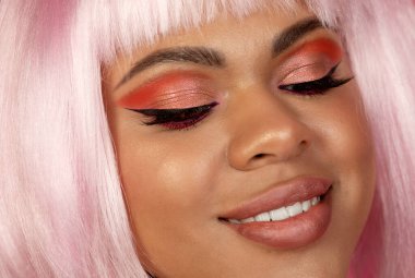 Yaratıcı makyajlı ve pembe saçlı güzel bir Afrikalı Amerikalı kızın yakın plan portresi.