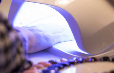 Yeni, güzel, modern jöle cilası manikürlü kadın ellerinin yakın görüntüsü. Tırnak cilasının üst kapağını iyileştirmek için el kaldıran kadın. Seçici odak.