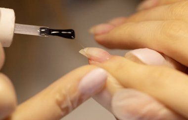 Manikürcünün güzellik salonundaki müşterilerini tedavi edişinin kısmi görüntüsü. Manikür, çivi boyama. Seçici odak.