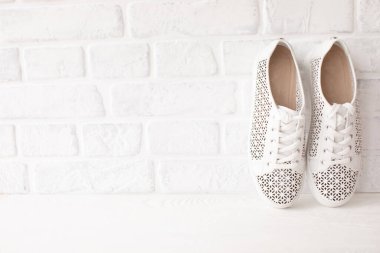 Açık tuğlalı duvar zemininde beyaz şık ayakkabıların yakın plan görüntüsü 