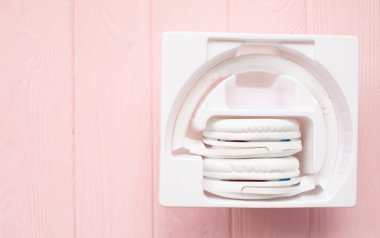 Pembe ahşap arka planda beyaz kulaklıklar.