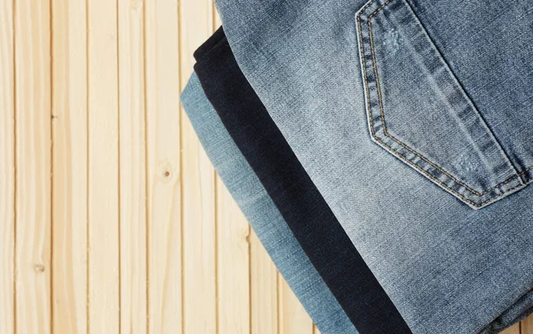 Pila Pantaloni Denim Elegante Sfondo Legno Con Spazio Copia Vista — Foto Stock