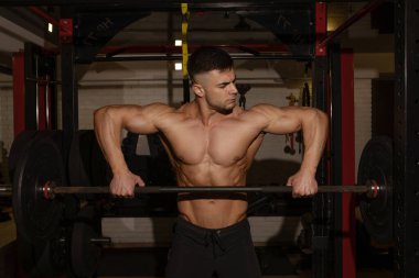 Spor salonunda halterli kaslı adam eğitimi. 