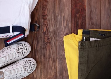 Kahverengi ahşap arka planda şık beyaz spor ayakkabılar ve giysiler   