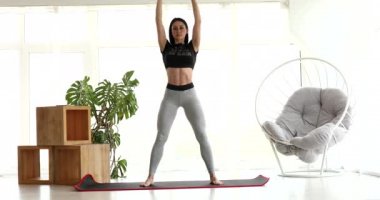 Evde egzersiz yapan genç bir kadın. Sportif esmer kadın evde beden eğitimi yapıyor..