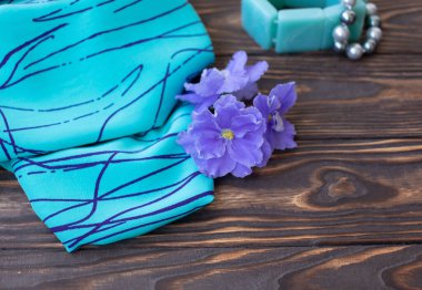 Parlak kumaş örneklerinin ve ahşap masadaki aksesuarların yakın plan görüntüsü.