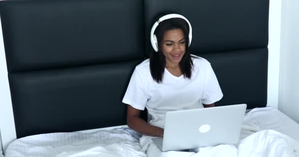 Usmívající Mladá Žena Sluchátkách Sedí Posteli Pomocí Notebooku — Stock video
