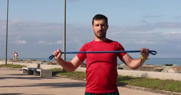 Giovane Fitness Uomo Caucasico Facendo Esercizio Con Elastico Sulla Costa — Video Stock