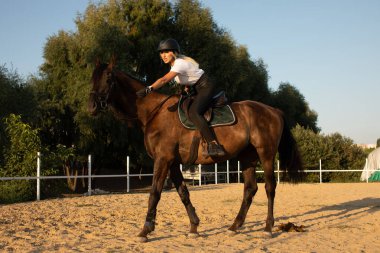 Güzel genç kız yarışma sırasında üniformalı ata biniyor.