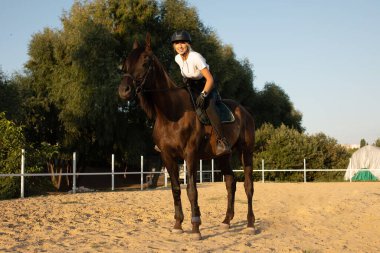 Güzel genç kız yarışma sırasında üniformalı ata biniyor.