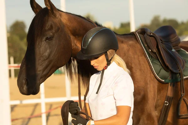 Güzel genç bir kadın ata binmeye hazırlanıyor, eğitmen ata bakıyor..
