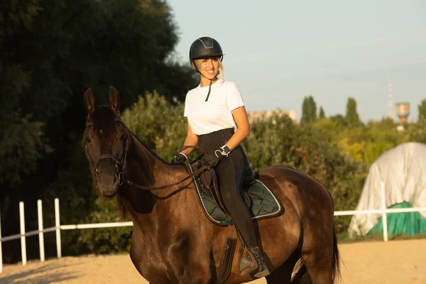 Çekici, gülümseyen genç bir kadın ata biniyor