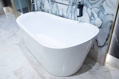 Lüks banyoda mermer duvarlı beyaz akrilik serbest küvet.