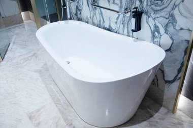 Lüks banyoda mermer duvarlı beyaz akrilik serbest küvet.