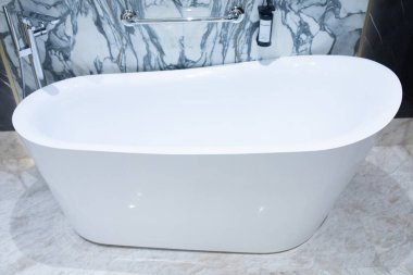 Lüks banyoda mermer duvarlı beyaz akrilik serbest küvet.