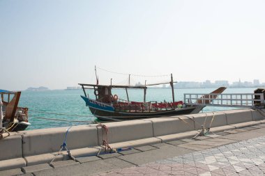 Katar 'daki Doha Corniche, geleneksel dhow tekneleriyle rıhtıma yanaştı ve arka planda şehrin silüeti vardı..