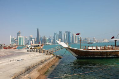 Katar 'daki Doha Corniche, geleneksel dhow tekneleriyle rıhtıma yanaştı ve arka planda şehrin silüeti vardı..