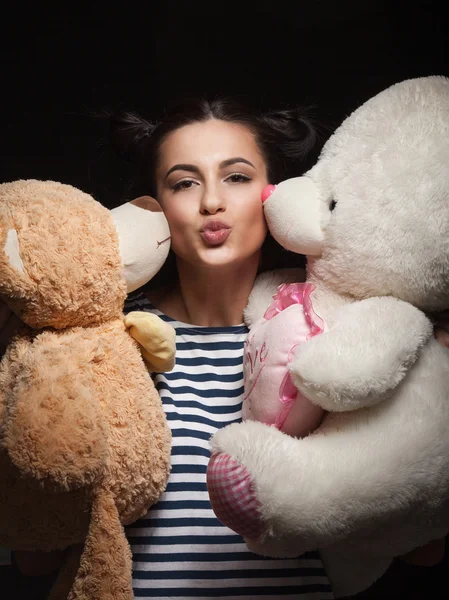 portrait of attractive caucasian smiling woman brunette with bear isolated on black studio shot