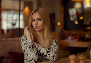 Bir kafede oturan sevimli sarışın gülümseyen kadın portresi