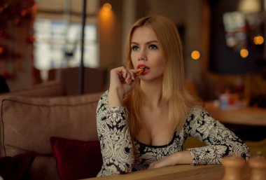 Bir kafede oturan sevimli sarışın gülümseyen kadın portresi