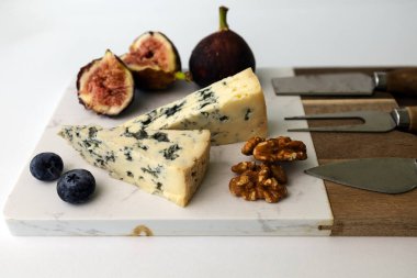 Peynir tahtasında küflü peynir Forme D 'ambert beyaz arka planda incir, ceviz ve yaban mersini